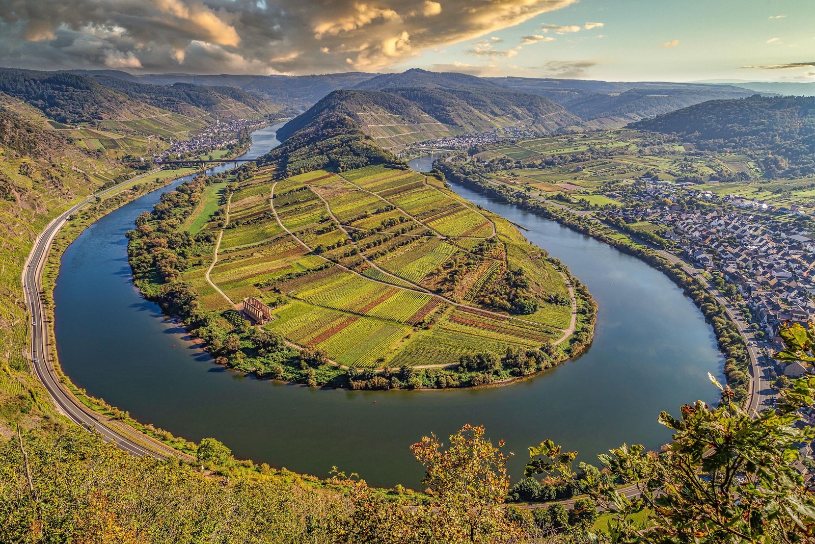 Scenic aerial shot of Moselle River's winding path through Bremm, Germany, showcasing lush vineyards.